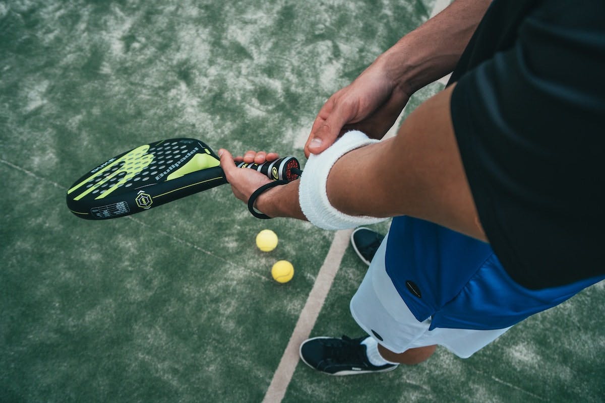 Billede af mand der spiller padel og døjer med en tennisalbue